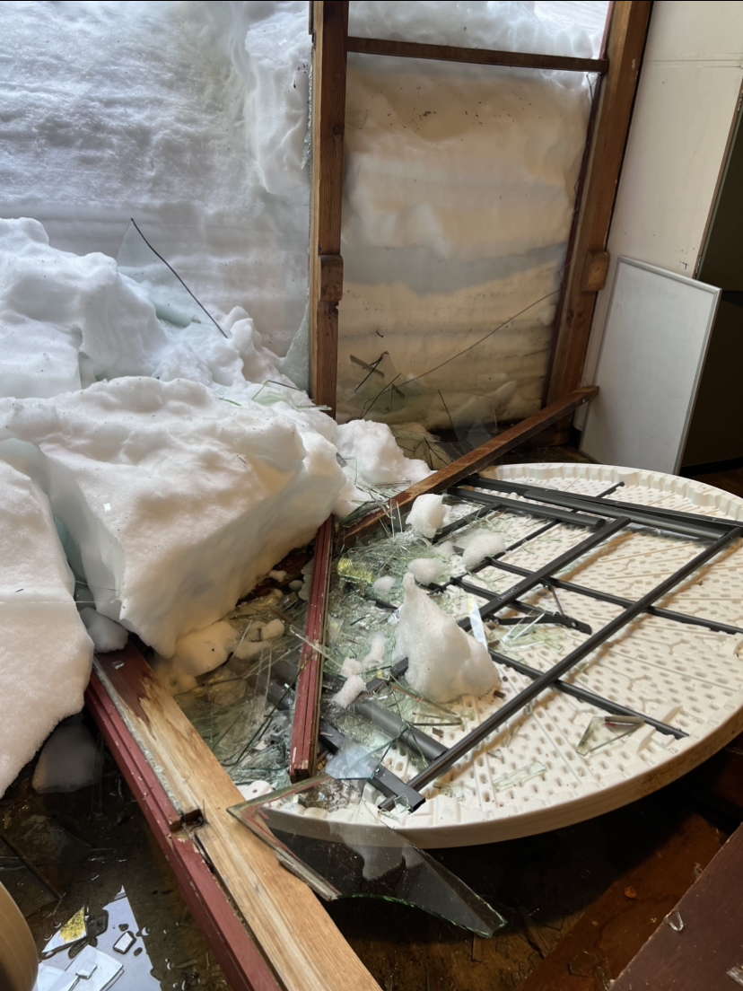 A white round table sits covered in glass and snow after the lodge windows shattered